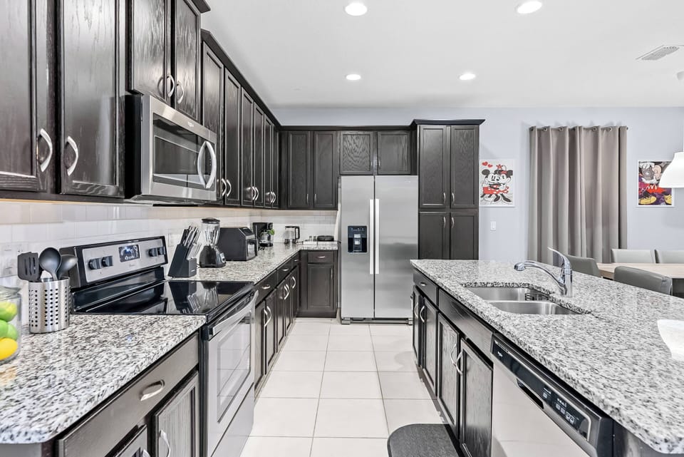 Enjoy a beautifully designed kitchen featuring rich dark cabinetry, sleek granite countertops, and stainless steel appliances. The polished tile flooring adds a stylish touch, making it perfect for your culinary adventures.
