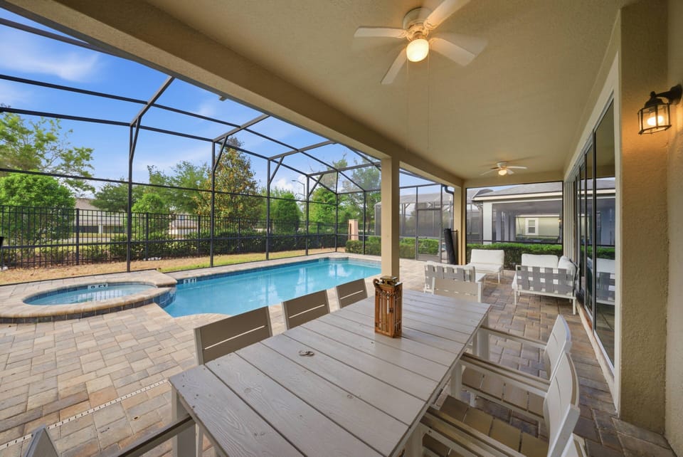 Enjoy the covered patio with a spacious dining table perfect for al fresco meals by the sparkling pool. The light-colored furniture contrasts beautifully with the lush greenery, creating a refreshing atmosphere for your.