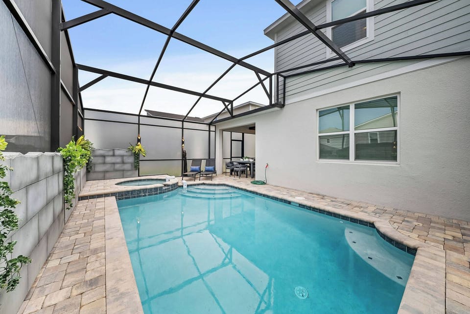 Step outside to your own private oasis, where a sparkling pool awaits under a spacious screened enclosure. The natural stone pavers add warmth, while lush greenery provides a touch of tranquility, perfect for soaking up the sun.