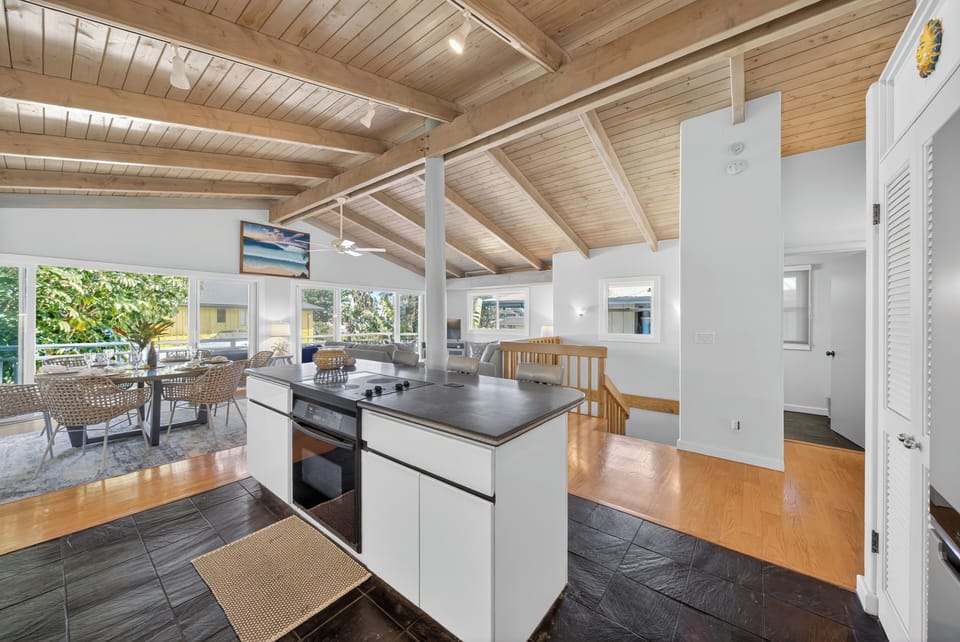 Enjoy the spacious, open-concept living area with its vaulted wood beam ceiling, natural light flooding through large windows, and cozy island for gathering.