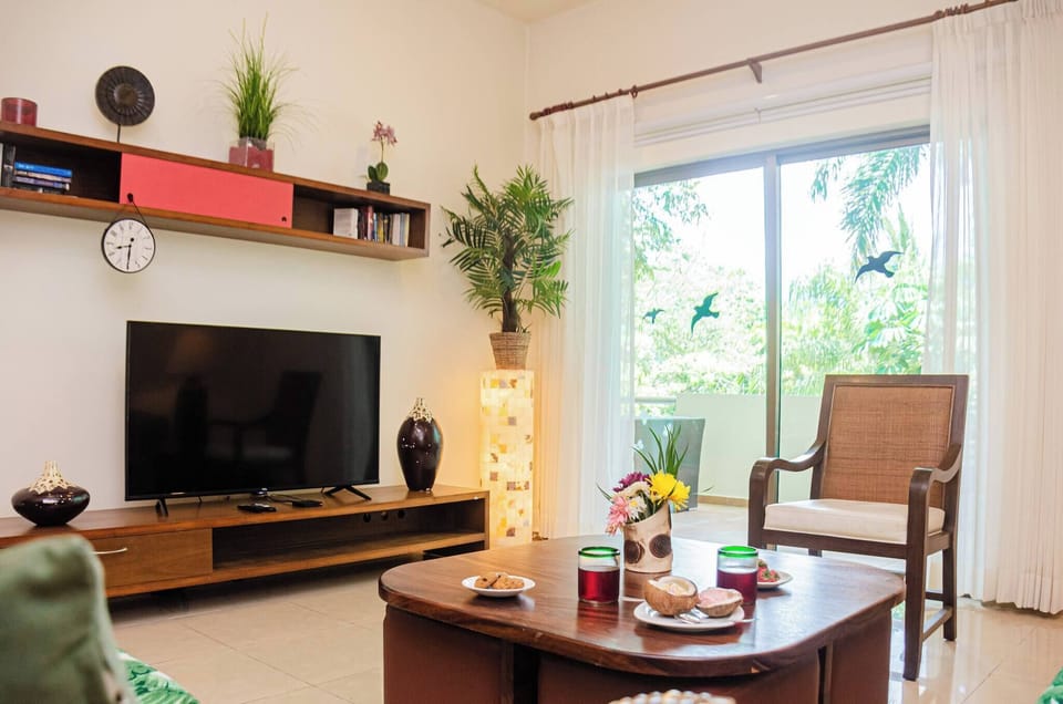 Spacious and well-lit living room with cable TV and comfortable furniture.