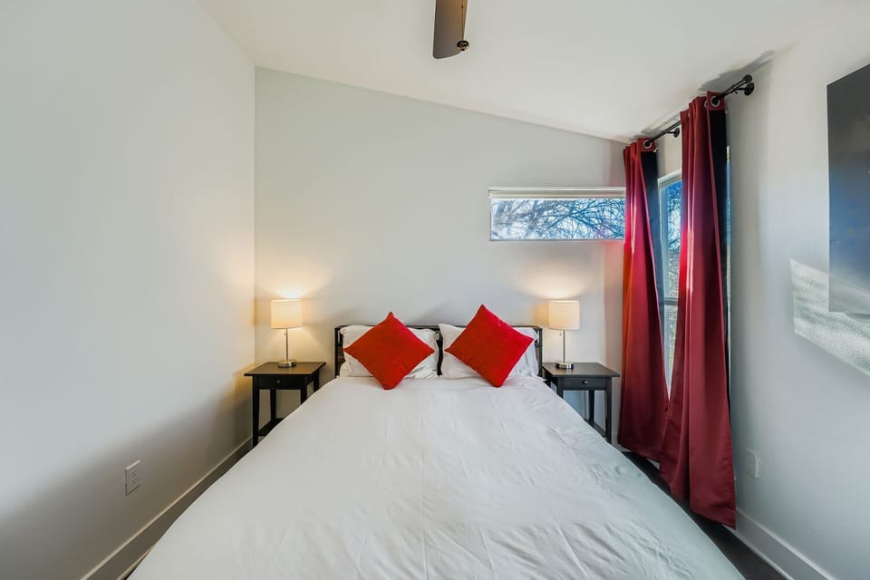 Bright primary bedroom with queen bed, ceiling fan, and natural light.