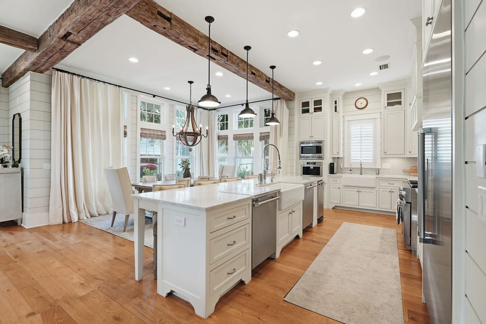 Step into a gourmet kitchen where rustic wood beams meet modern elegance, inviting you to cook and gather with loved ones in timeless farmhouse style.