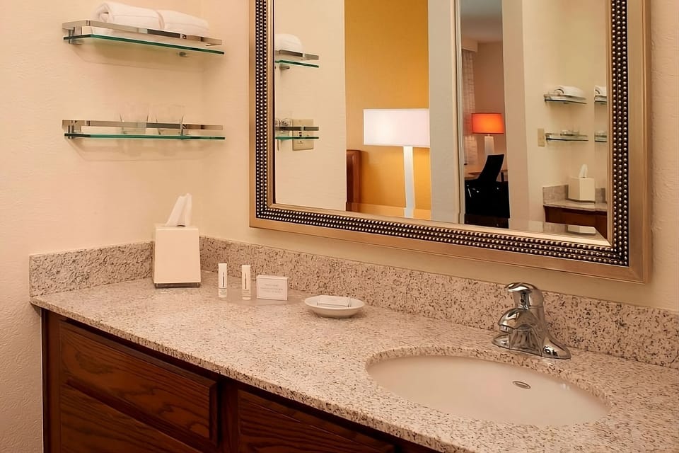 Refresh at a wide granite vanity with bright mirror lighting.