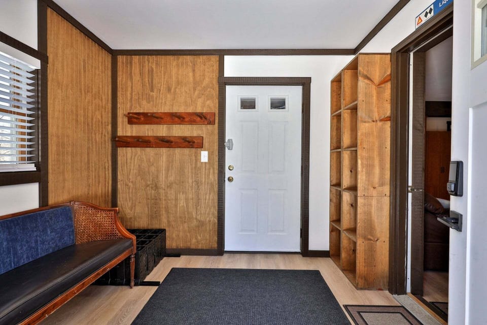 Wall pegs, open cubbies, and a bench organize coats, shoes, and bags near the door.