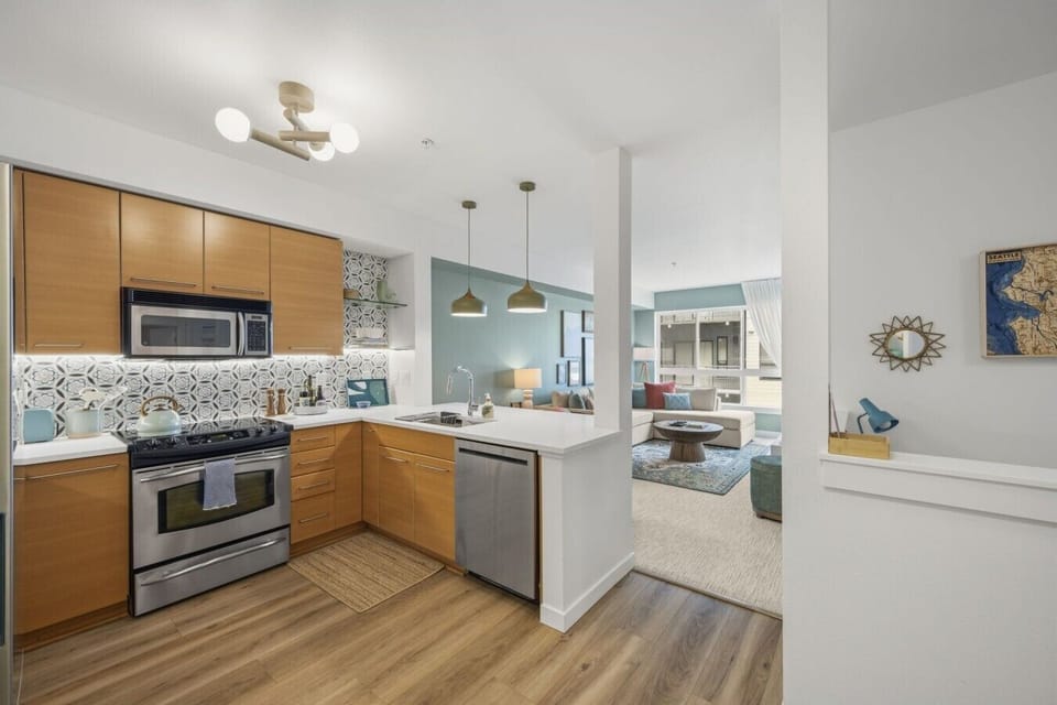 Fully equipped modern kitchen with stainless steel appliances, spacious countertops, bar seating, pendant lighting, cookware, and everything needed for cooking meals at home.