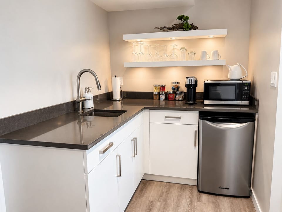 Kitchenette with bar fridge, bar sink and coffee bar with Nespresso machine.


