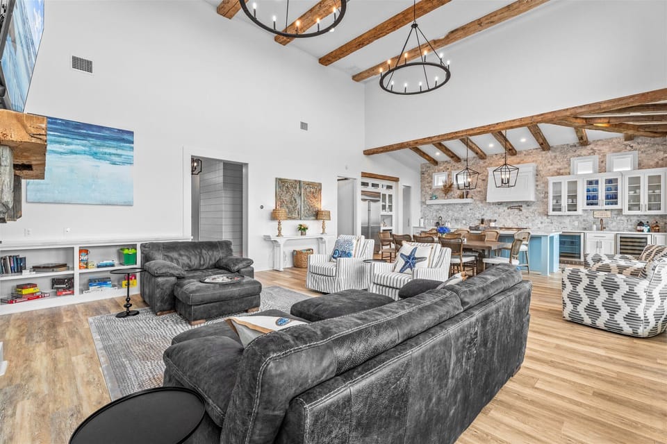 Open-concept family room with plush sectional seating, designer chandelier lighting, and airy coastal farmhouse interior design.