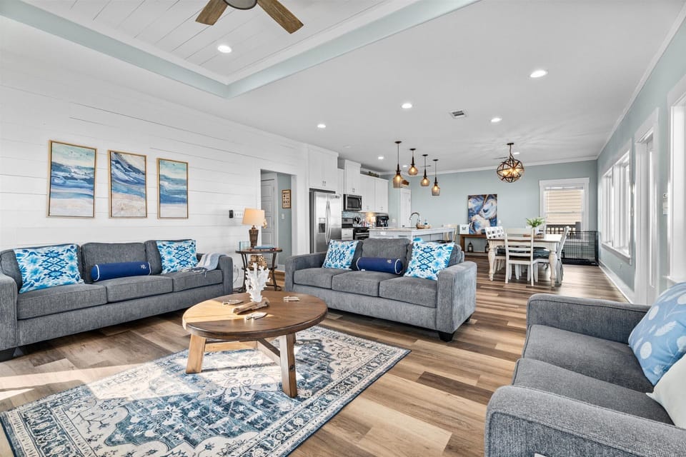 Modern beachfront living room with comfortable sofas, hardwood floors, coastal accents, and spacious layout designed for relaxing Texas beach vacations.