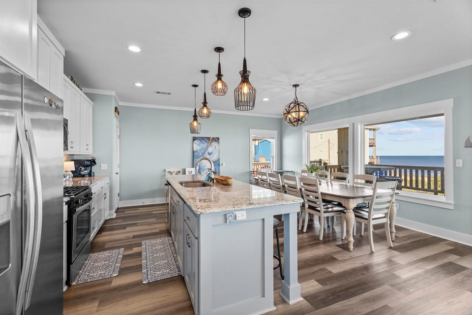 Fully equipped gourmet kitchen with stainless steel appliances, large island, pendant lighting, and open dining space perfect for family meals and entertaining.