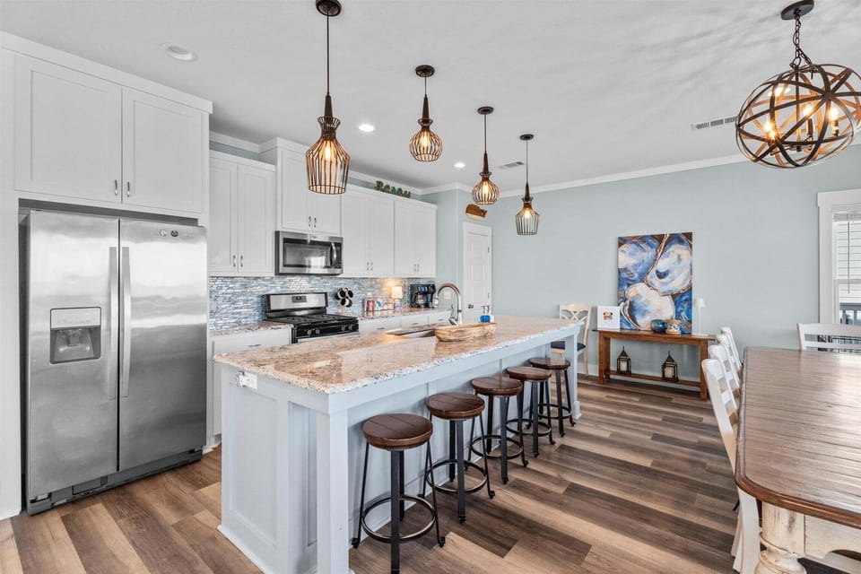 Spacious beach house kitchen with oversized breakfast bar, modern cabinetry, stainless steel appliances, and seating for large vacation groups.