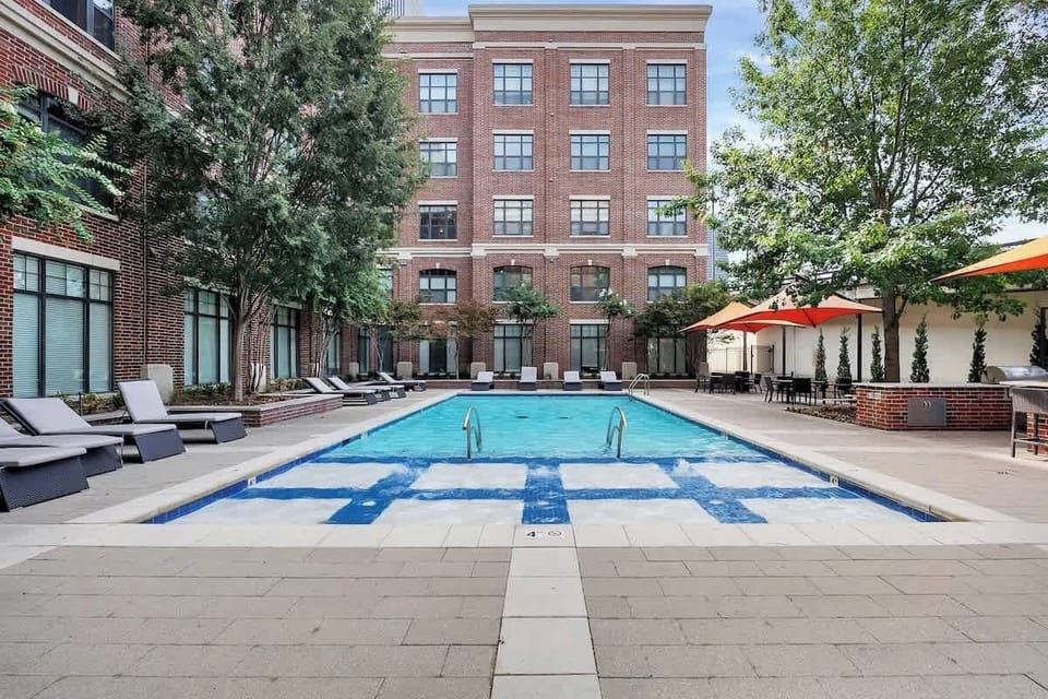 Outdoor pool area with lounge seating, shaded tables, and a relaxing courtyard-style setting.