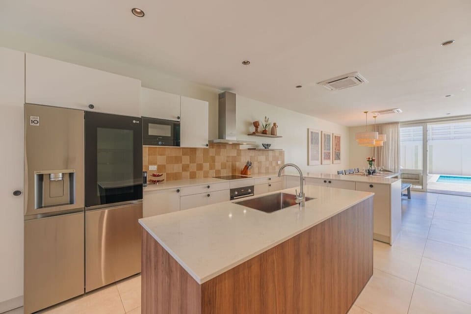 Modern kitchen with island seating, stainless steel appliances, and bright open plan design.