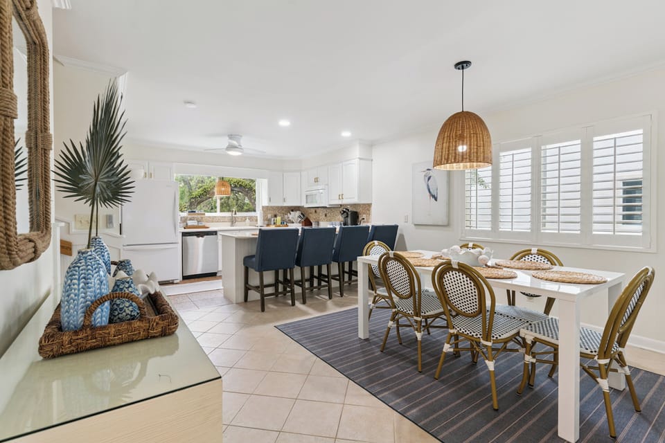 Gather around this bright, coastal-inspired space where your group can share meals and stories. The open layout connects kitchen to dining, making every moment feel effortlessly social and relaxed.