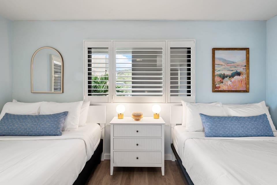 Secondary bedroom with two beds, coastal decor, and bright window light.