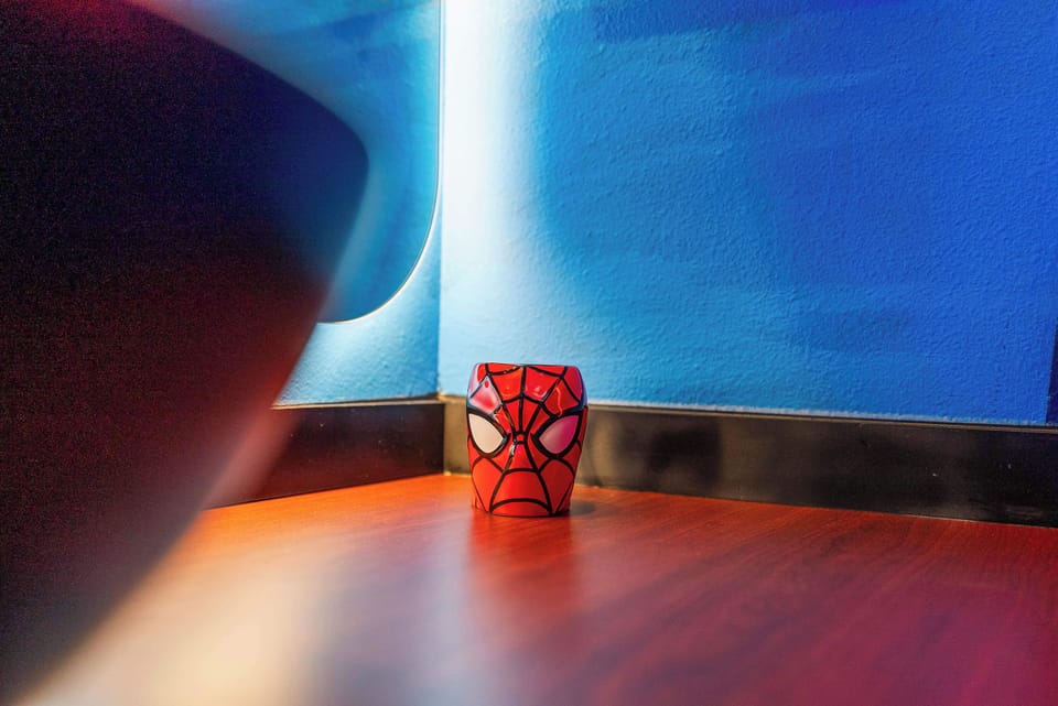A spiderman-themed cup on a wooden surface against a blue wall adds a playful touch to the room.