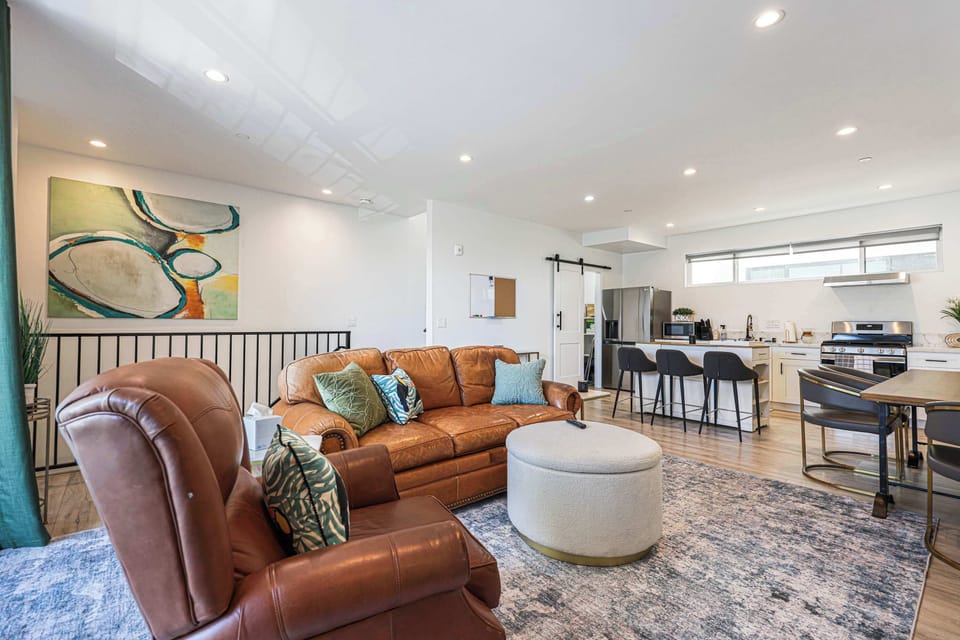 Unwind on leather seating in a bright, airy living space that flows into a modern kitchen with island seating, perfect for morning coffee or evening cocktails.
