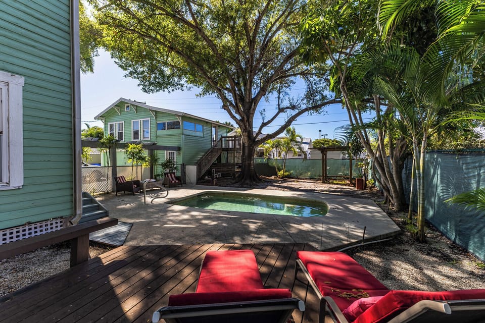 Relax by the shared pool, featuring comfy lounge chairs and shady trees.
