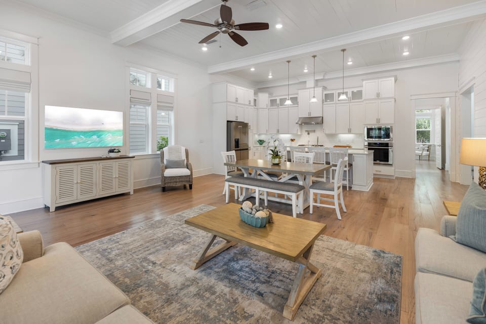 Your open-concept living space flows beautifully with coastal charm, where soft seating, polished hardwood, and vaulted ceilings invite you to relax in comfort and style.