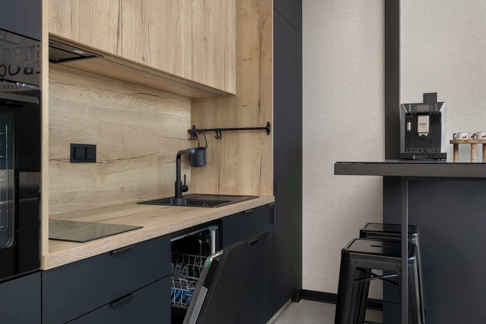 A stylish kitchenette with dark cabinets, wooden details, and modern appliances. The interior feels sleek and contemporary.