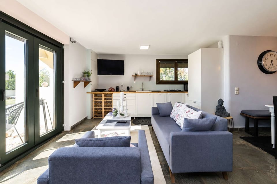Open interiors and wide windows create an easy flow between the kitchen, living area, and outdoor landscape throughout the day.