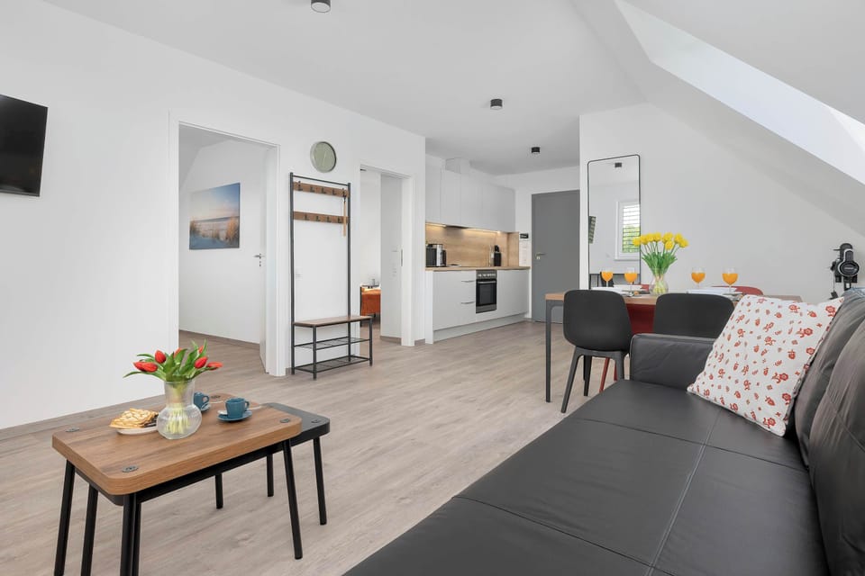 Looking from the kitchen toward the entrance, this angle highlights the open layout of the apartment. A clothes hanger stand is visible near the doorway, leading into the living and dining areas.
