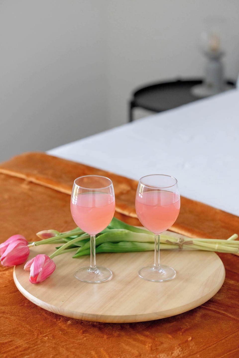 A small decorative setup with glasses and flowers on a wooden surface. Soft colors create a warm and elegant mood.