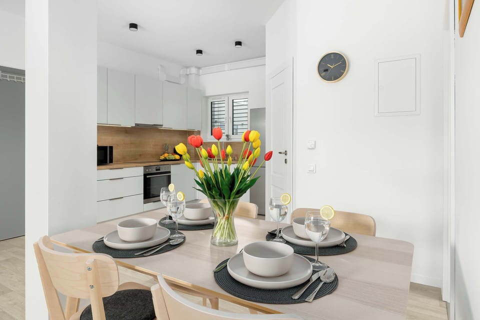A dining table set with plates, glasses, and flowers. The modern interior looks elegant and welcoming.