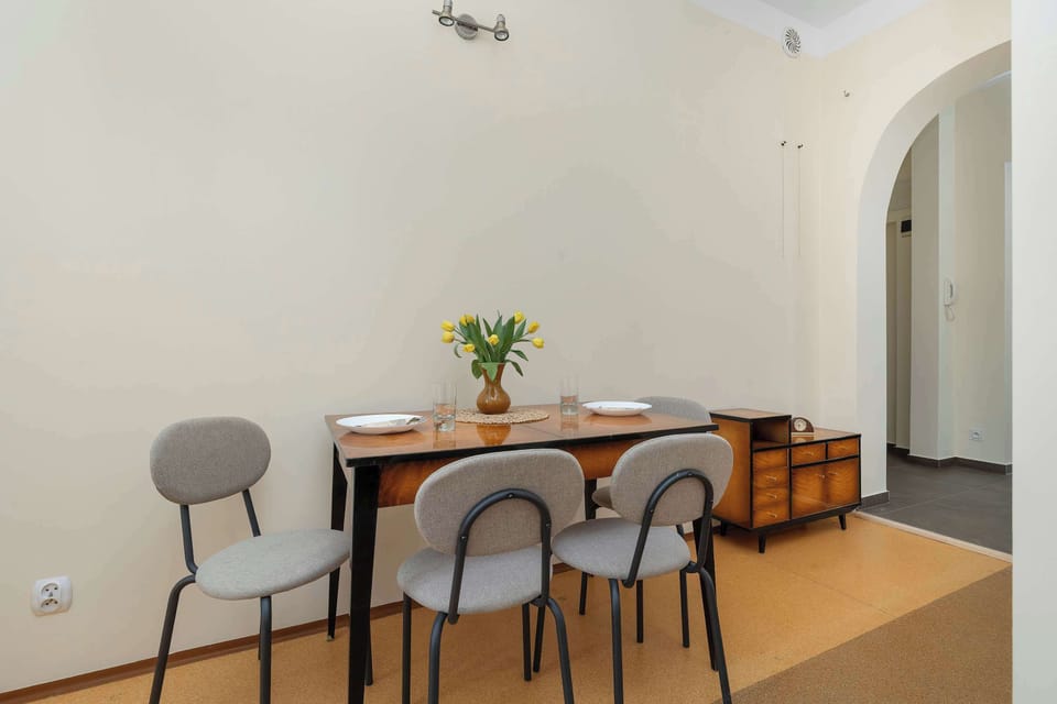 A compact dining nook with a small table and chairs positioned beside an arched hallway. Minimal décor and soft colors create a functional dining area.