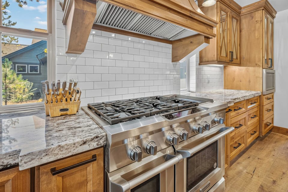 Step into your gourmet kitchen featuring a professional-grade gas range, gleaming granite counters, and custom wooden cabinetry that makes cooking and entertaining feel effortless and inspiring.