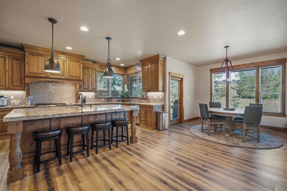 Step into your gourmet kitchen with warm wood cabinetry, granite counters, and a spacious island with bar seating. Enjoy preparing meals while natural light pours in, then gather with loved ones at the elegant dining table nearby.