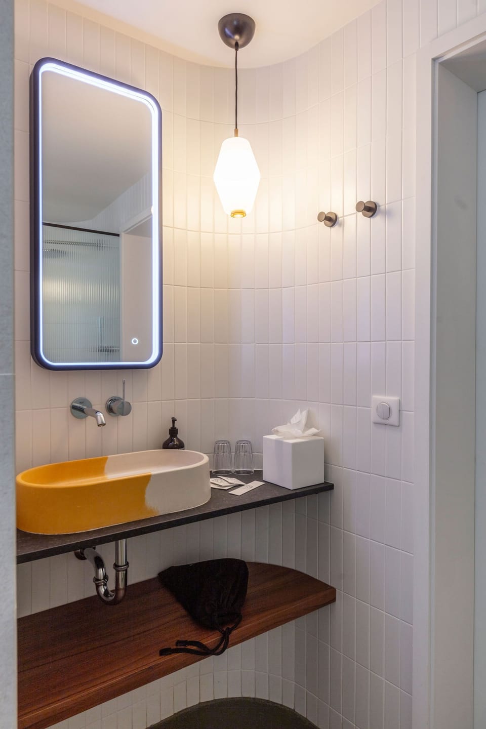 Oval sink on a dark countertop with a round mirror and modern wall lighting in the en-suite