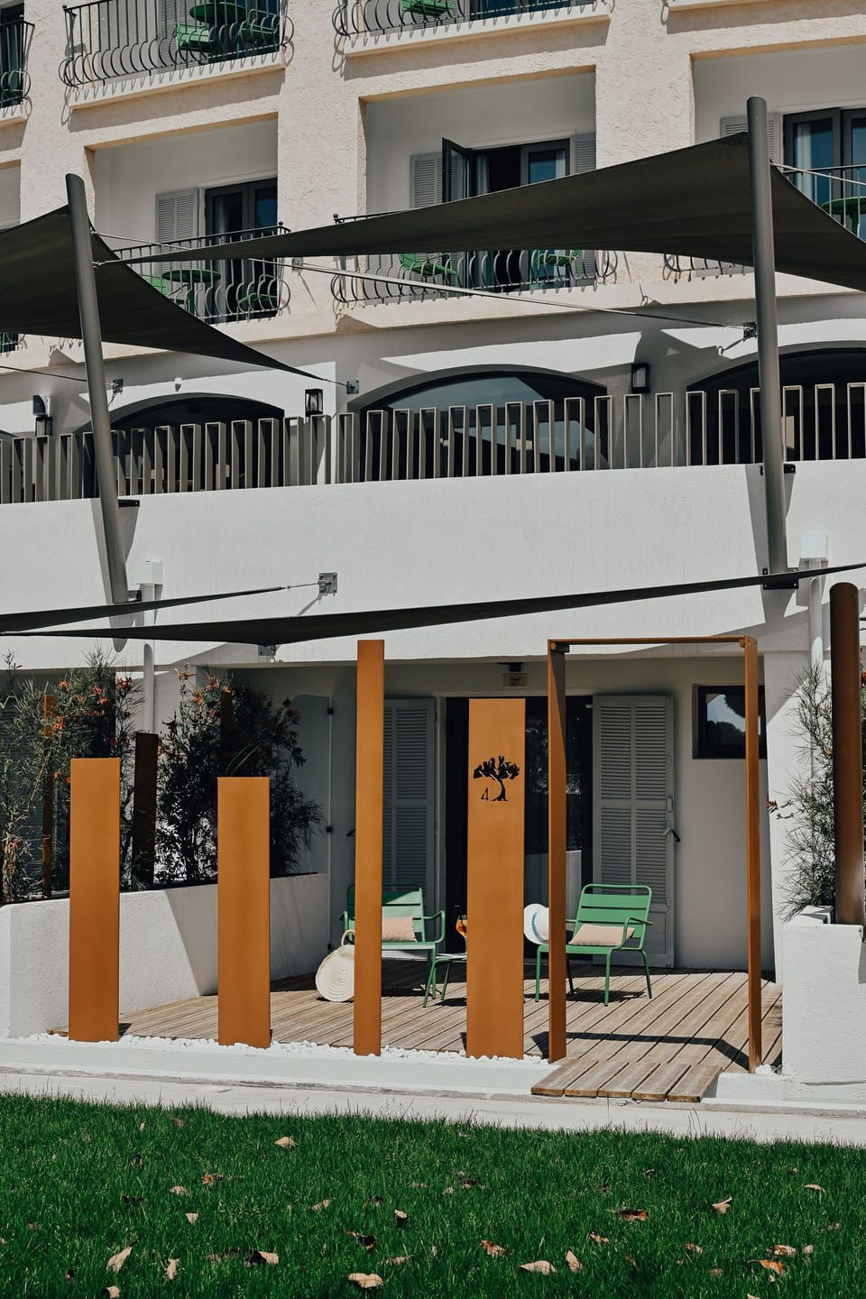 The terrace enclosed by vertical metal panels — green seating and open lawn just beyond