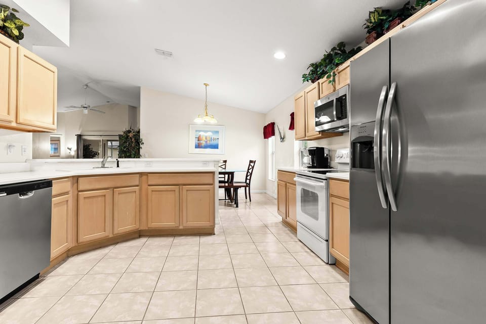 Spacious kitchen with stainless steel appliances and light wood cabinetry.