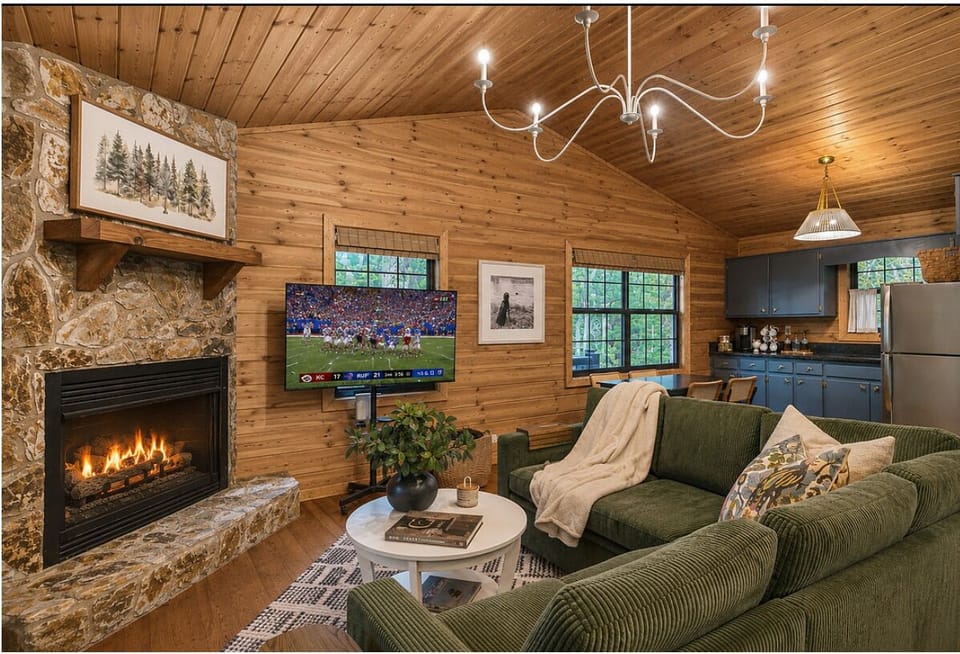 Cozy cabin lounge with fireplace, smart TV, and chic open kitchen