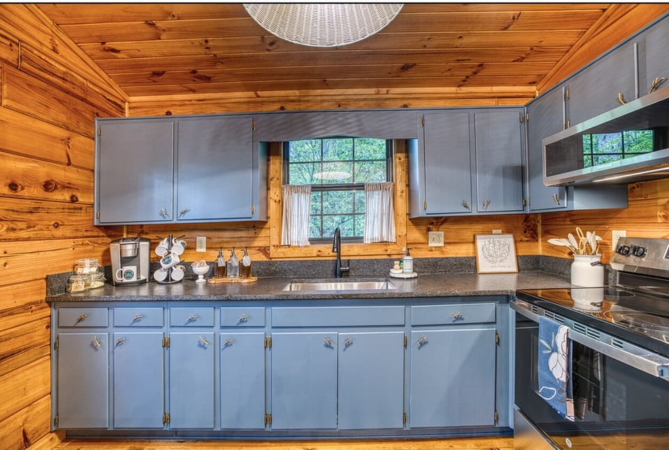 Charming cabin kitchen with blue cabinets, coffee bar, and stainless appliances