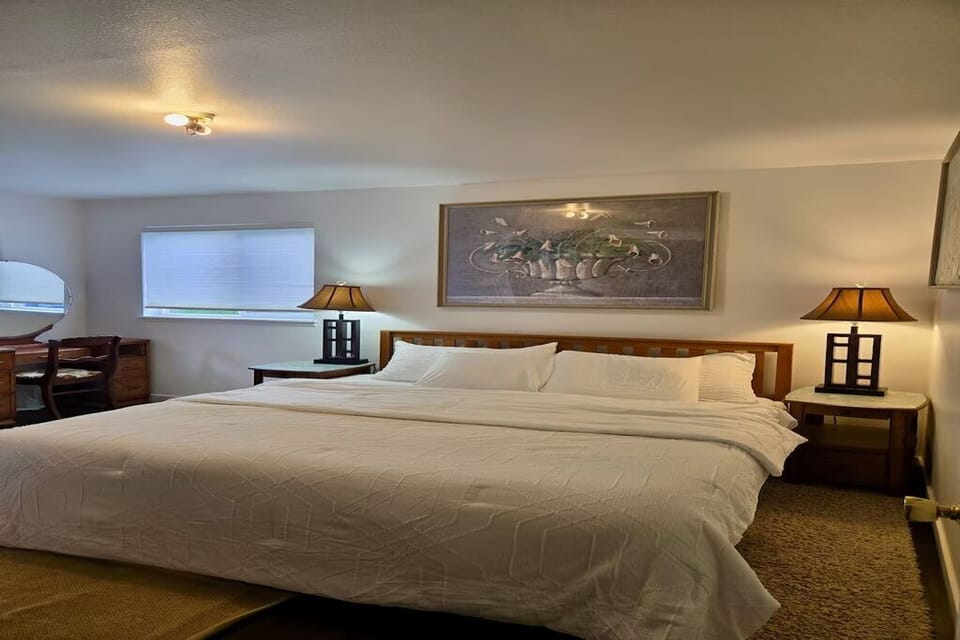 Spacious bedroom featuring a comfortable bed, dedicated vanity, ample storage, and large windows that fill the room with natural light. A peaceful retreat designed for rest and relaxation.
