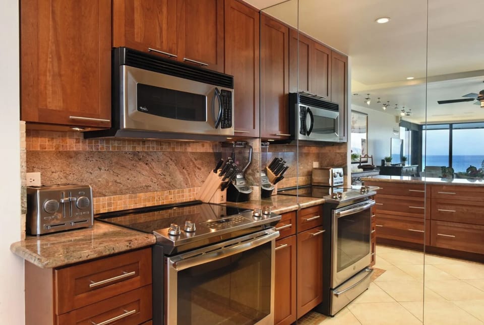 Unit 1: A fully equipped kitchen featuring stainless steel refrigerator, dishwasher, and elegant wood cabinetry