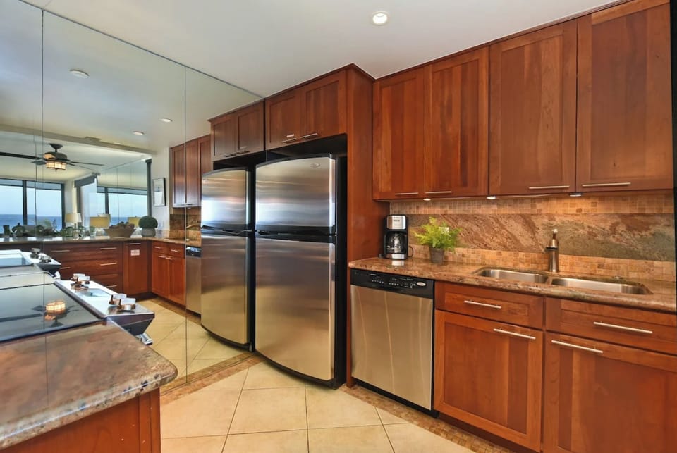 Unit 1: A fully equipped kitchen featuring stainless steel refrigerator, dishwasher, and elegant wood cabinetry