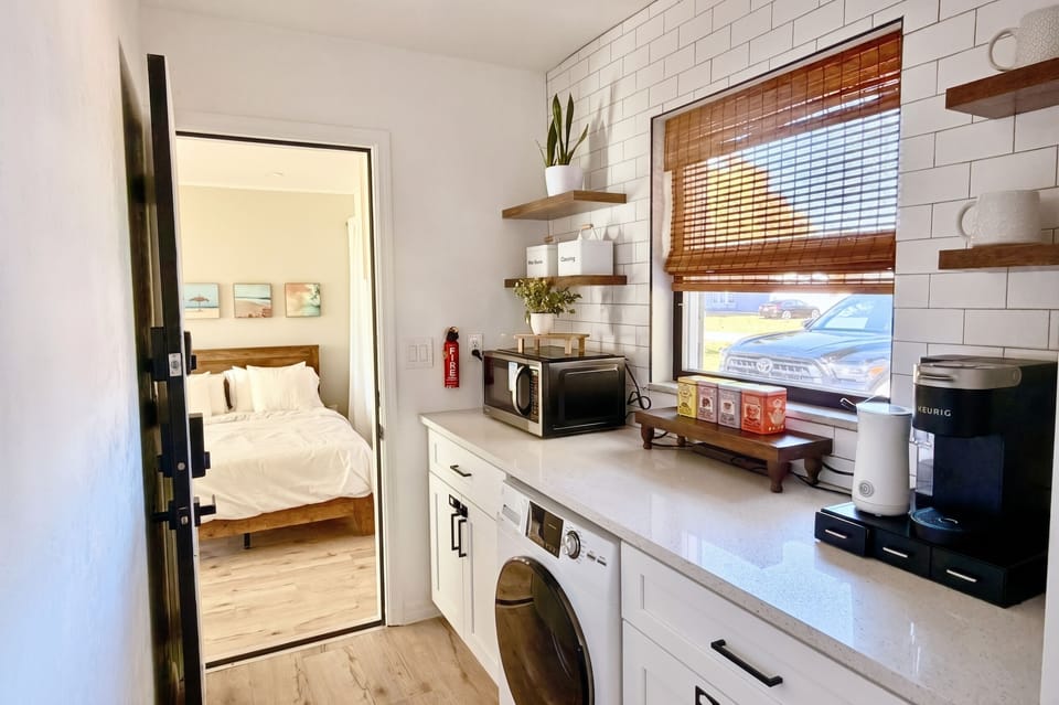 Guest suite kitchenette with a microwave and mini fridge, bedroom beyond
