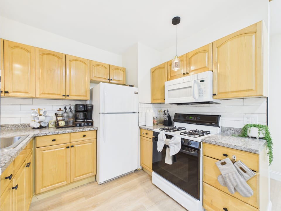 Bright full kitchen with gas stove, coffee station, and warm wood cabinets
