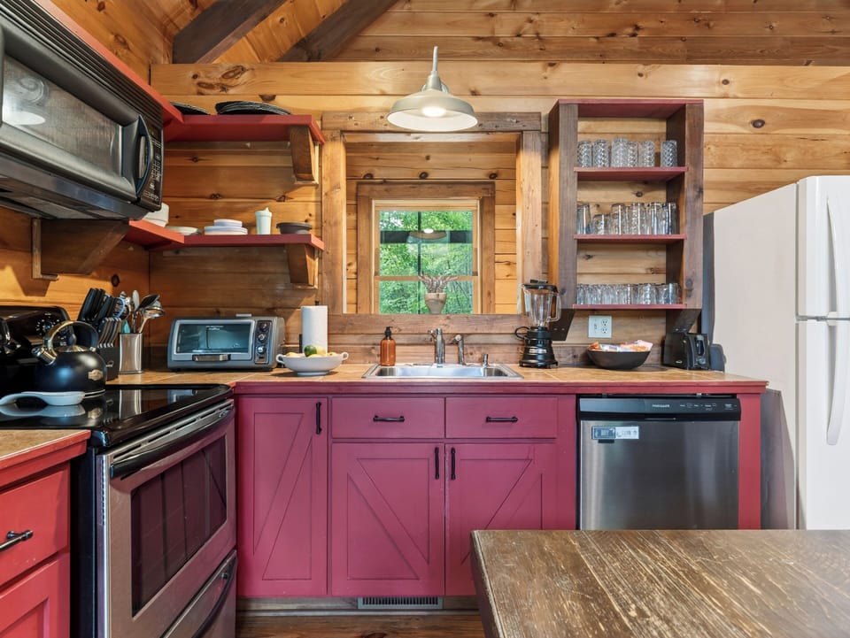Rustic kitchen with warm wood finishes, red cabinetry, and everything needed for easy cabin meals.