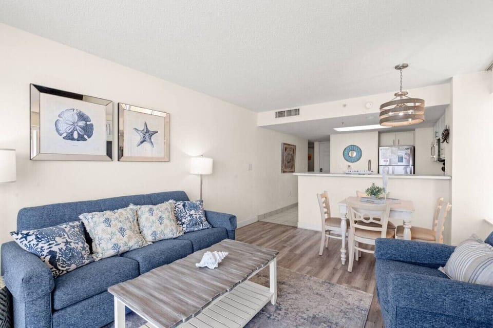 Open floor plan featuring the dining area, oceanfront living room, and full kitchen with bar seating, perfect for entertaining and relaxing by the beach.