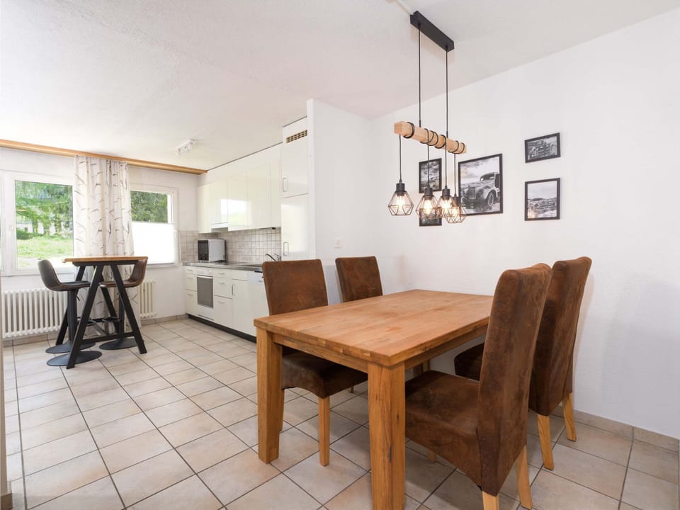 Dining area with wooden table, comfortable chairs and open connection to the living room and kitchen
