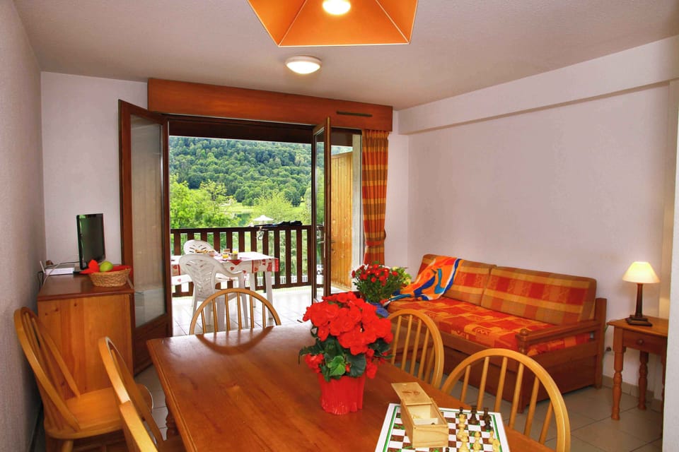 The bright living area with balcony access is perfect for unwinding after a day hiking around Lake Génos in summer or skiing in Val-Louron during winter.