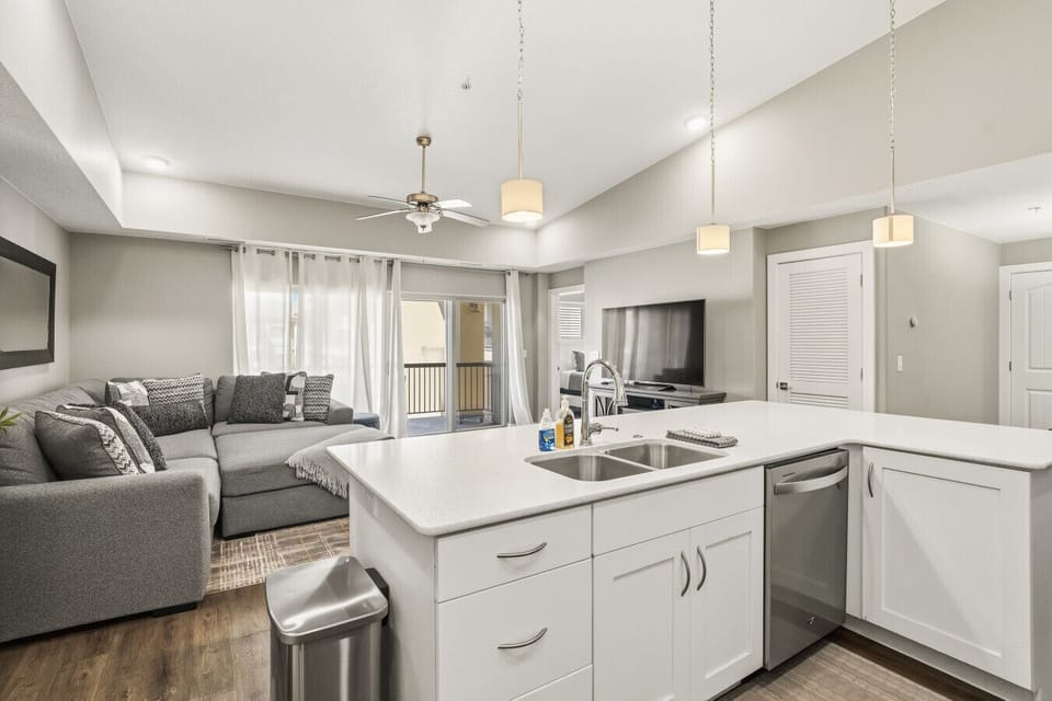 Open kitchen with island, living area, modern lighting, and spacious layout.