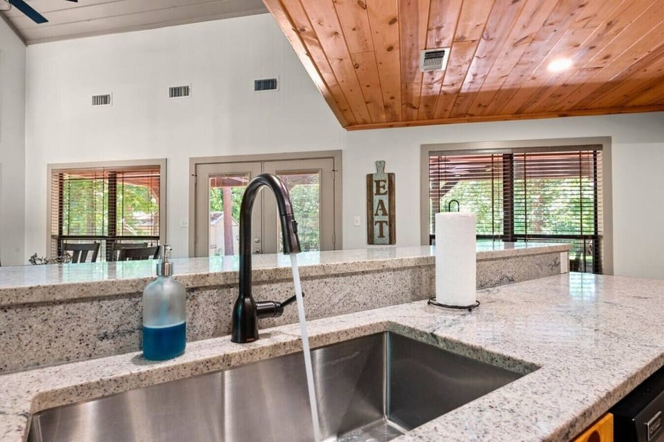 Modern kitchen island with granite counters, open dining area, and forest views