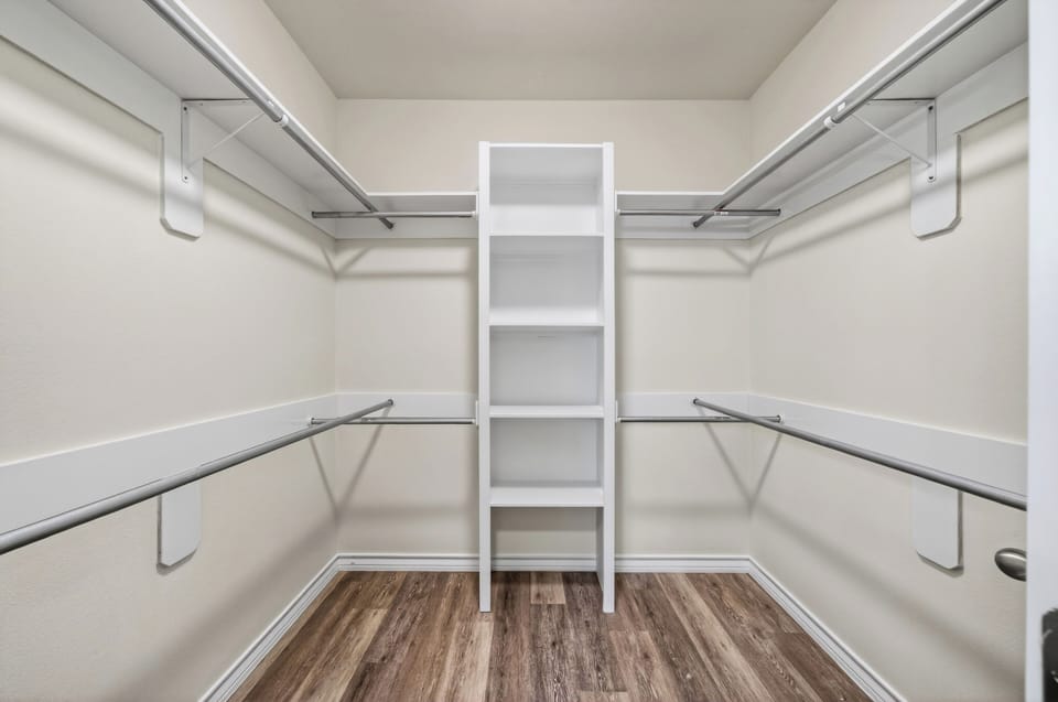 Expansive, custom-built walk-in closet with extensive shelving and multi-level hanging rods.