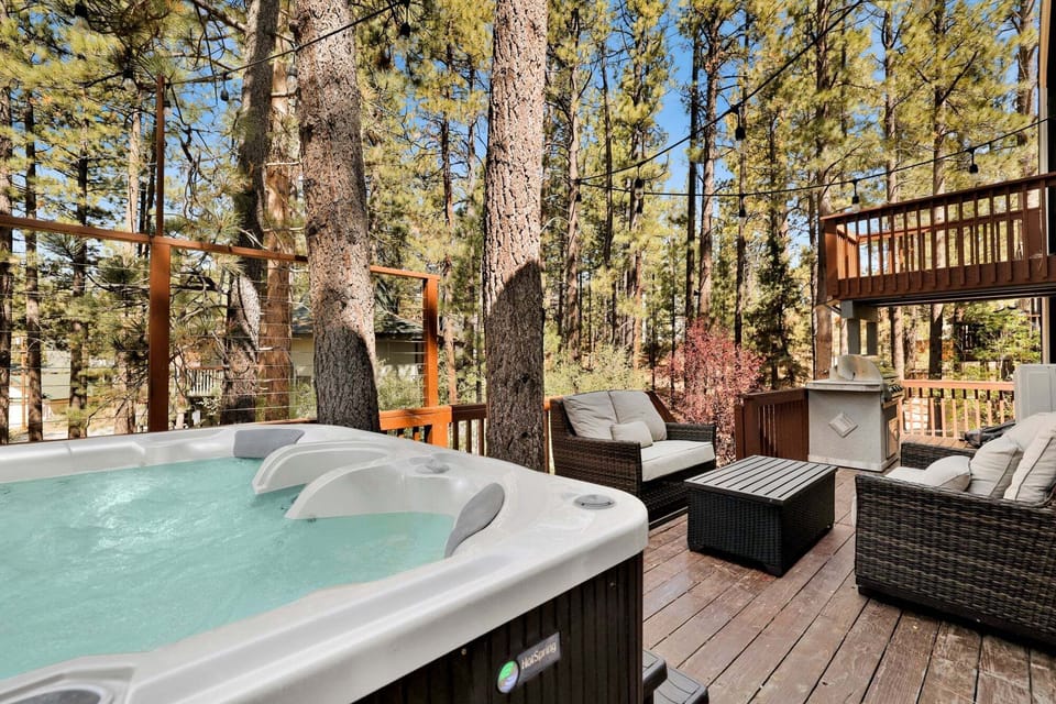 Cozy backyard with comfortable chairs, a BBQ grill, hot spa, and relaxing views of the surrounding pine trees and peaceful outdoor scenery.