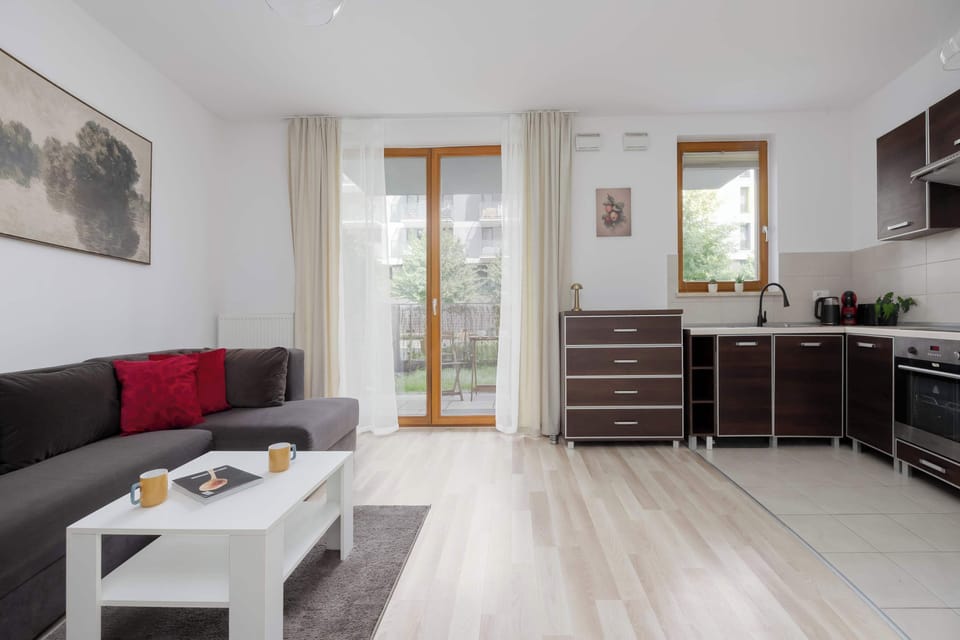 A modern apartment with an open kitchen, living area, and dining space arranged efficiently. Contemporary furnishings and white walls give the room a fresh appearance.